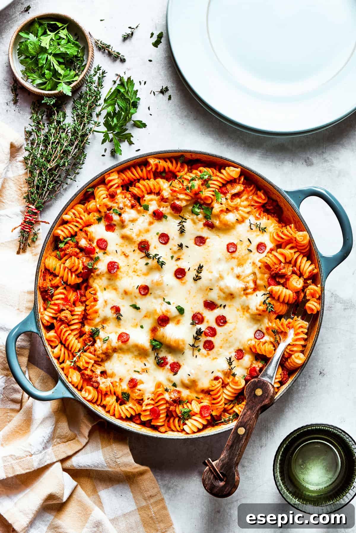 Wide shot of a baking dish with pasta topped with melted cheese and pepperoni, viewed from above.