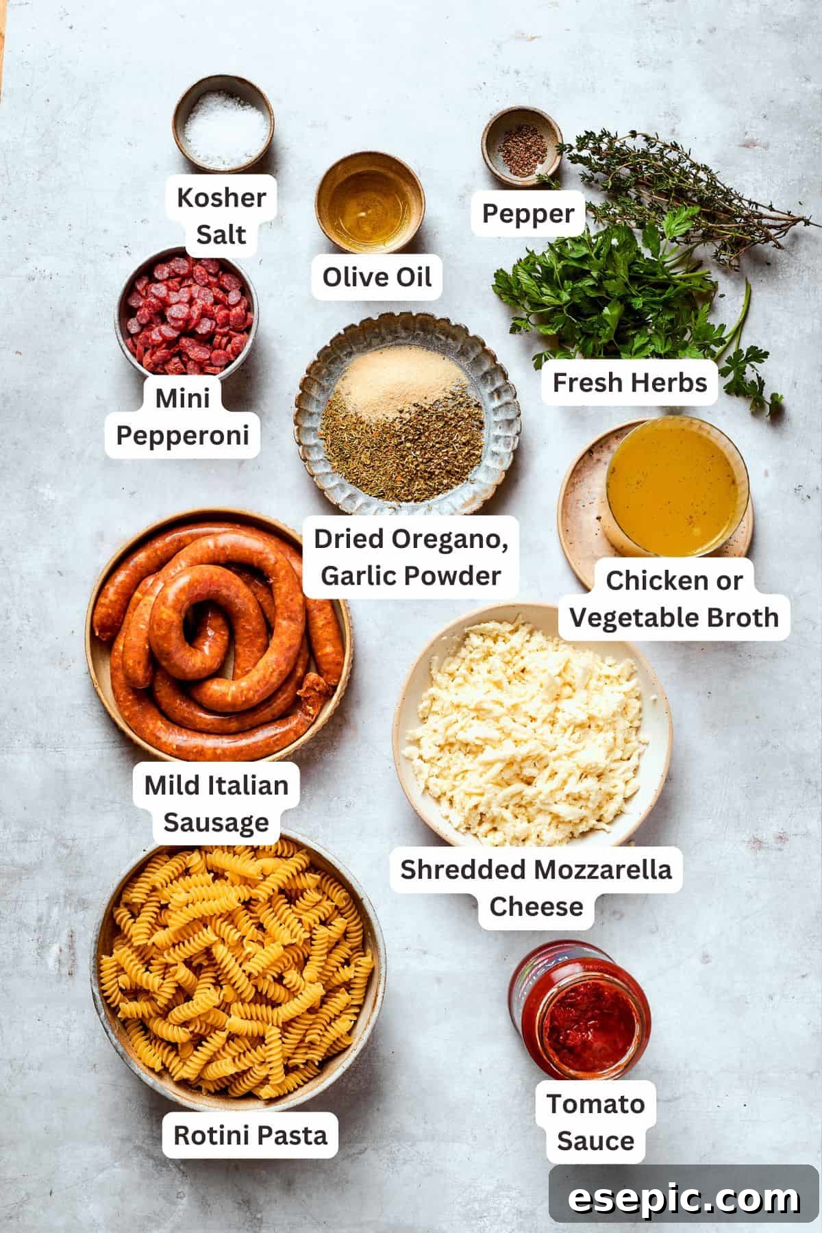 Ingredients for pizza pasta are portioned out and text-labeled on a white surface.