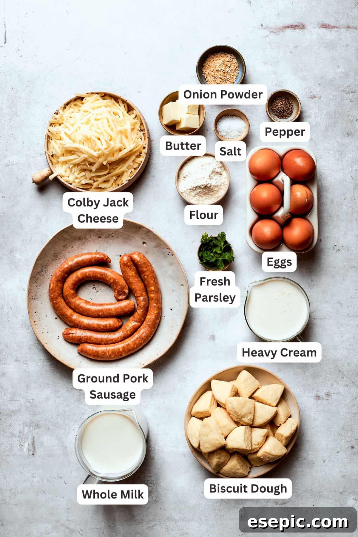 Ingredients for biscuits and gravy casserole are clearly laid out and text-labeled, including biscuits, sausage, butter, flour, milk, eggs, heavy cream, cheese, and parsley.