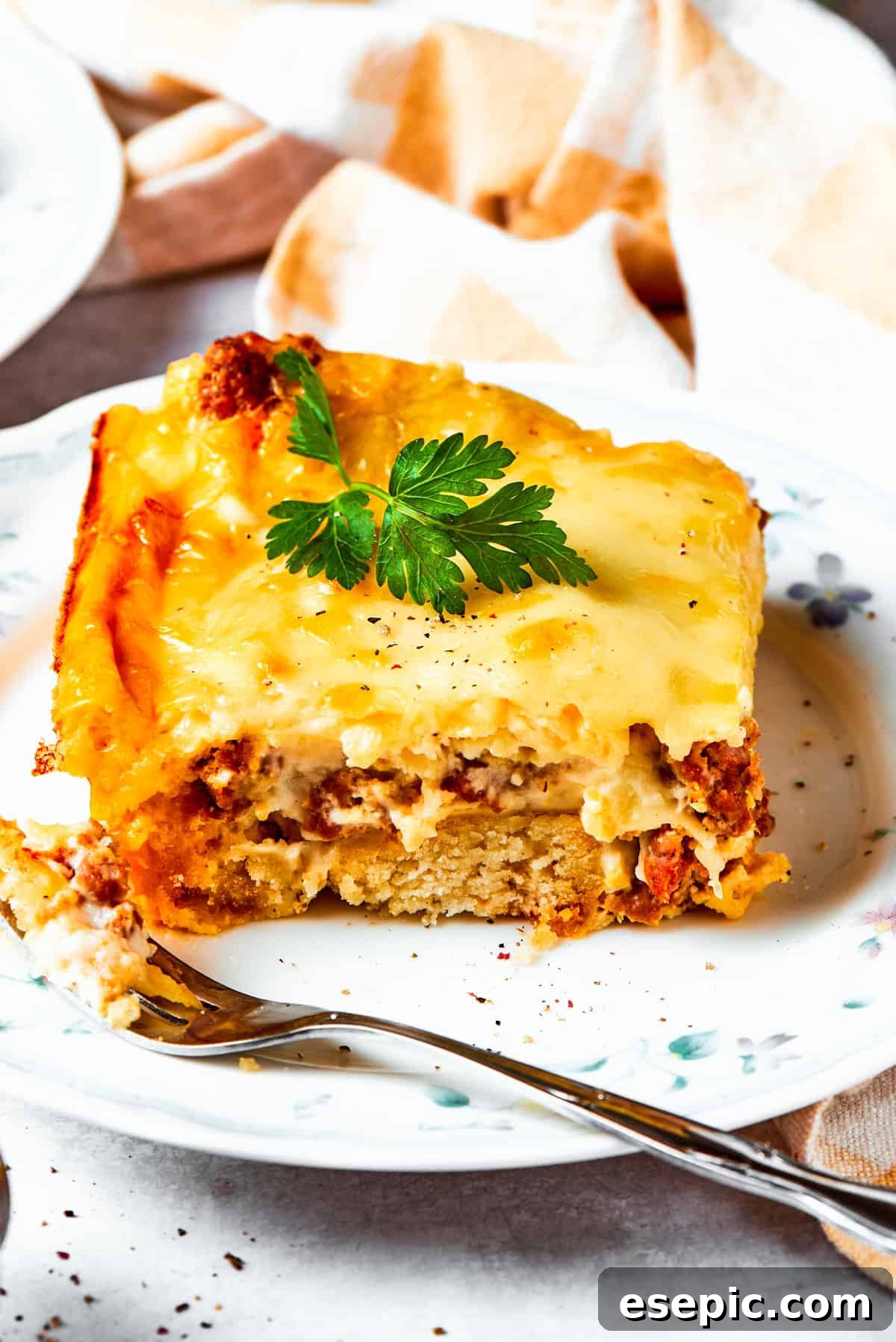 A perfectly portioned slice of biscuits and gravy casserole, showcasing its layers, served on a dinner plate, ready to be enjoyed.