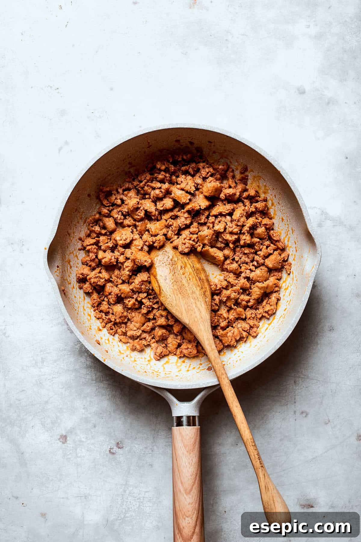 Ground pork sausage browning in a large skillet, broken into crumbles.