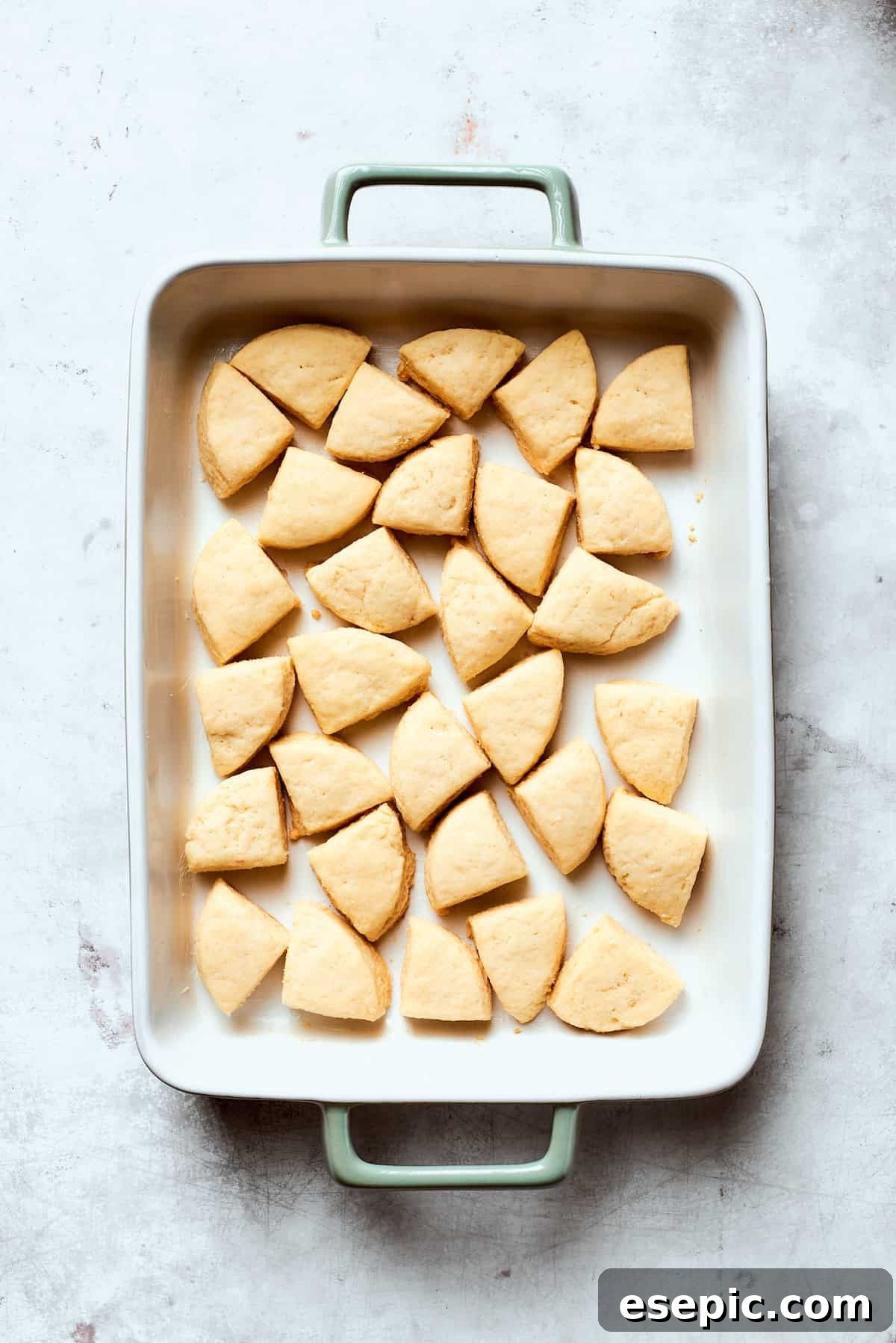 Pieces of refrigerated biscuit dough cut into quarters and arranged evenly in a greased 9x13 inch baking pan.