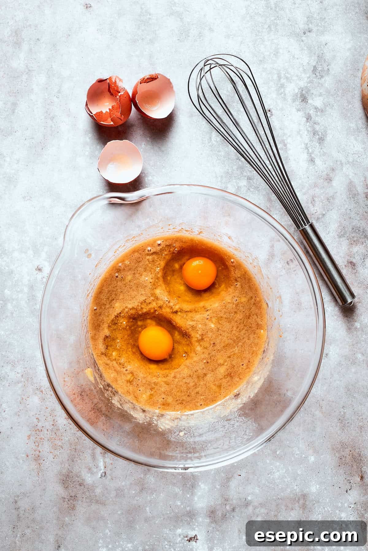 Two eggs are added to banana bread batter.