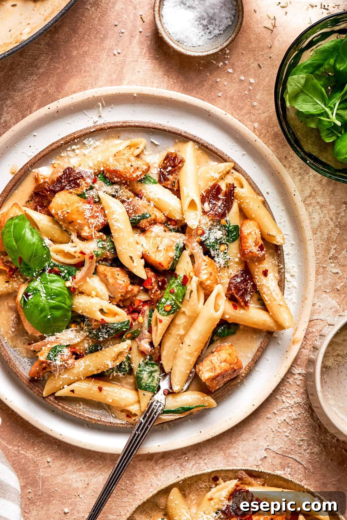Cheesy, marry me chicken pasta features tender bites of chicken swirled in a creamy sauce along with sundried tomatoes and pasta. Basil leaves garnish a big plate of marry me chicken pasta.
