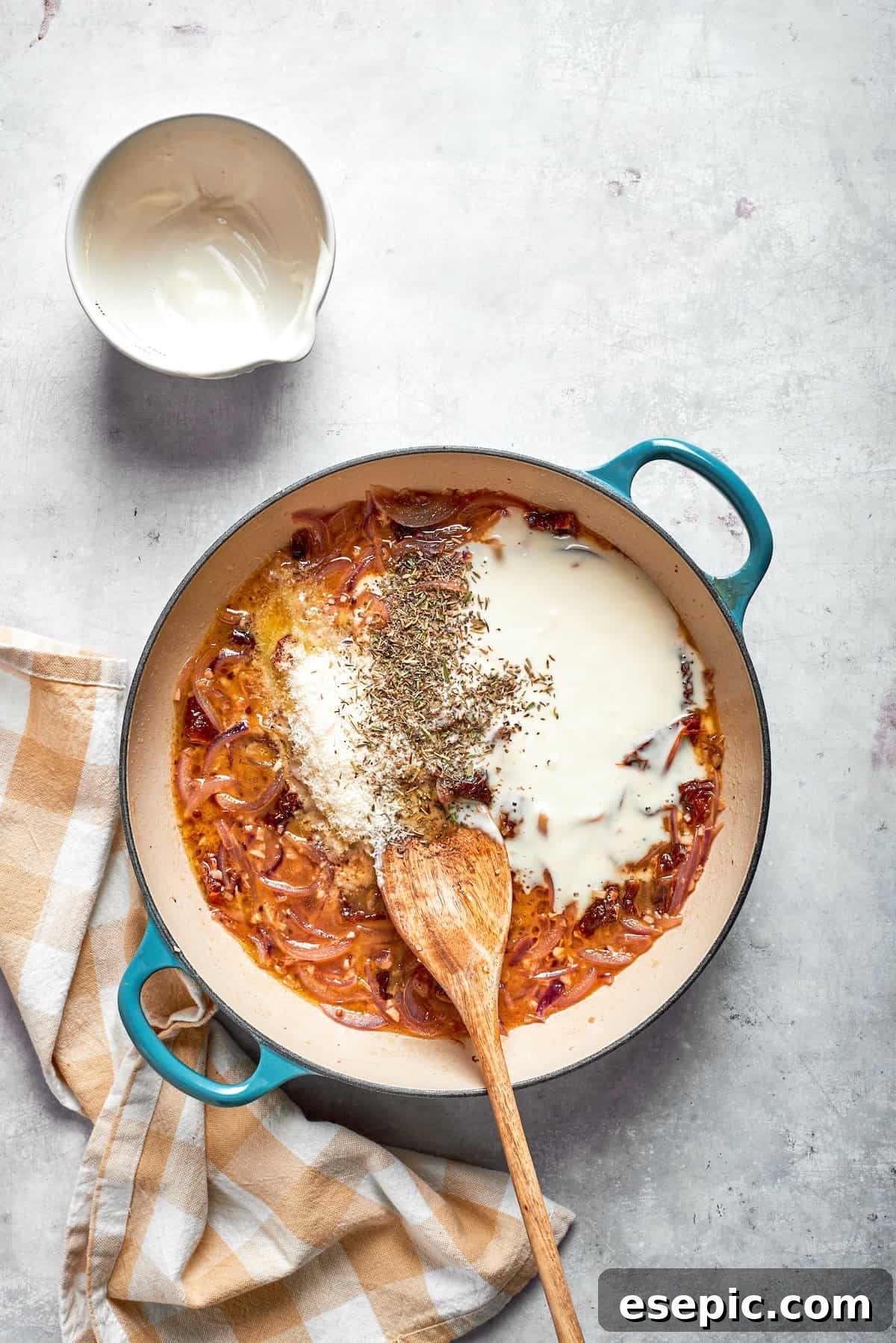 Cheesy, marry me chicken pasta features tender bites of chicken swirled in a creamy sauce along with sundried tomatoes and pasta. Cream is added to a skiilet for sauce.