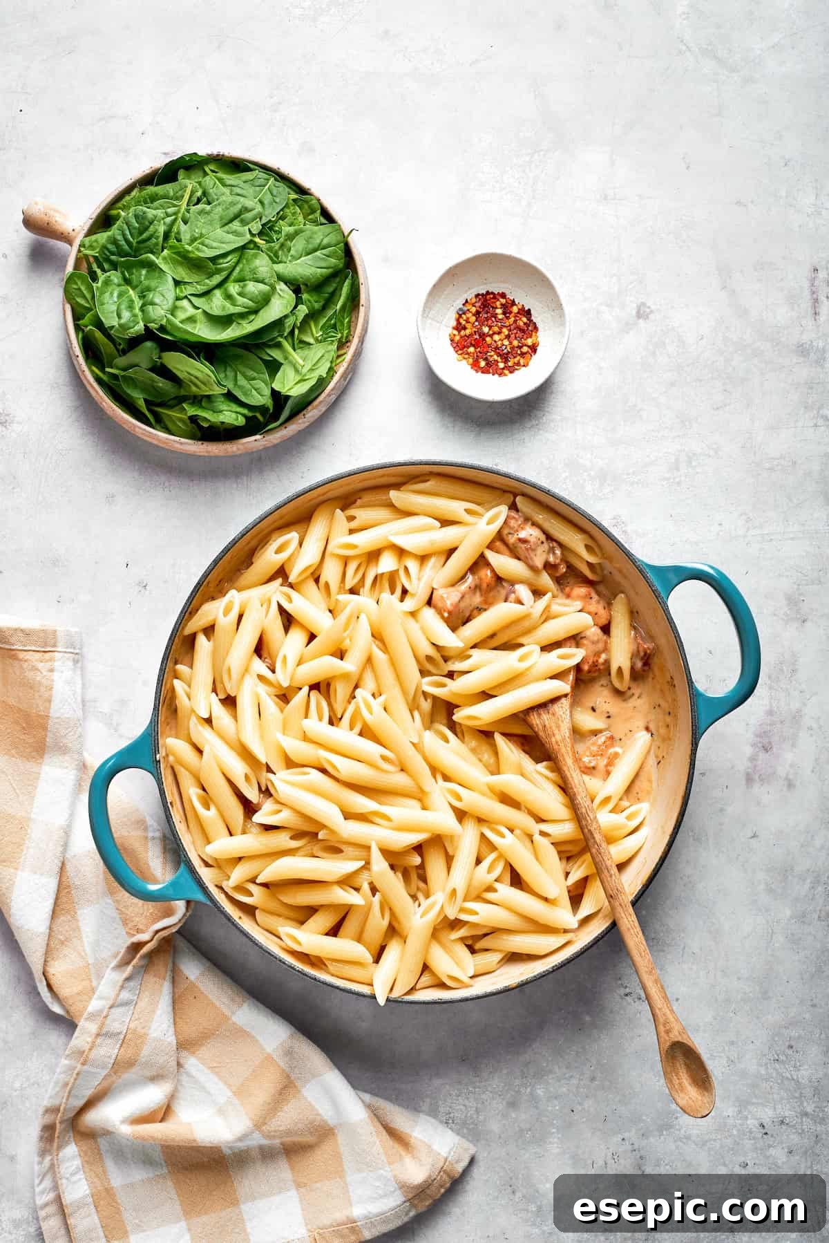 Cheesy, marry me chicken pasta features tender bites of chicken swirled in a creamy sauce along with sundried tomatoes and pasta. Pasta is stirred into cream sauce in a skillet.