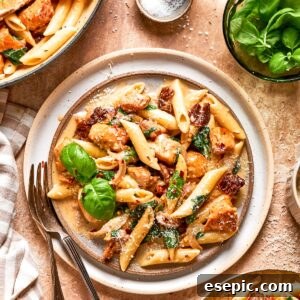 A plate of marry me chicken pasta garnished with fresh basil.