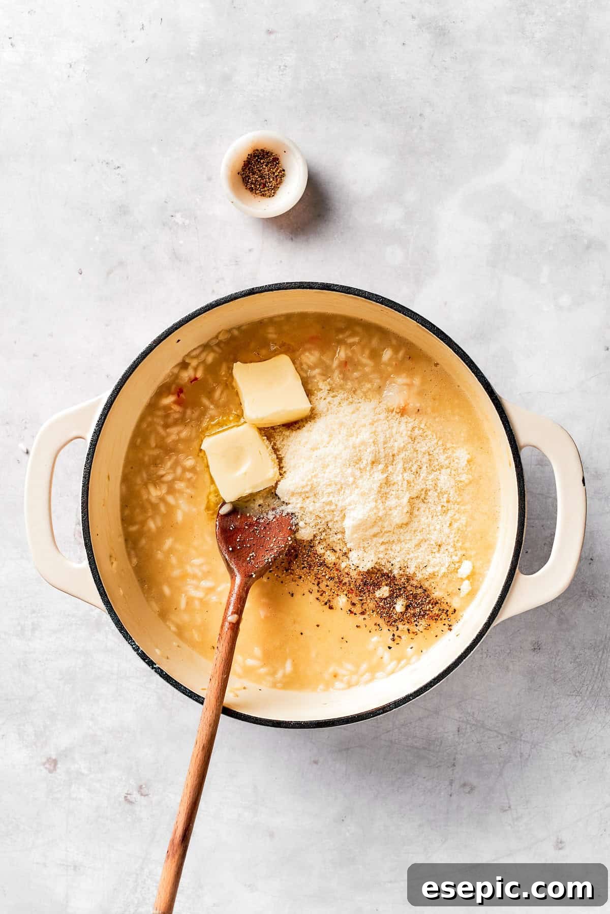 Stirring in the remaining butter, grated Parmesan cheese, and lemon juice into the finished shrimp risotto.