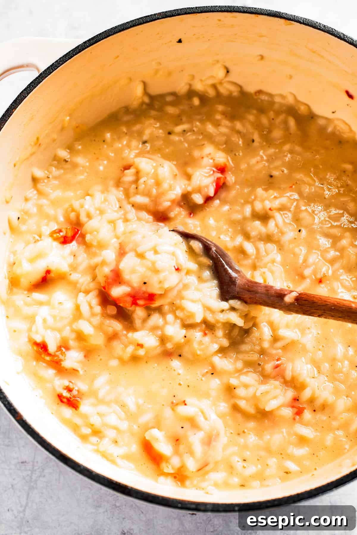 A close-up shot of a pot of rich, creamy shrimp risotto, being stirred with a wooden spoon, showcasing its perfect texture.