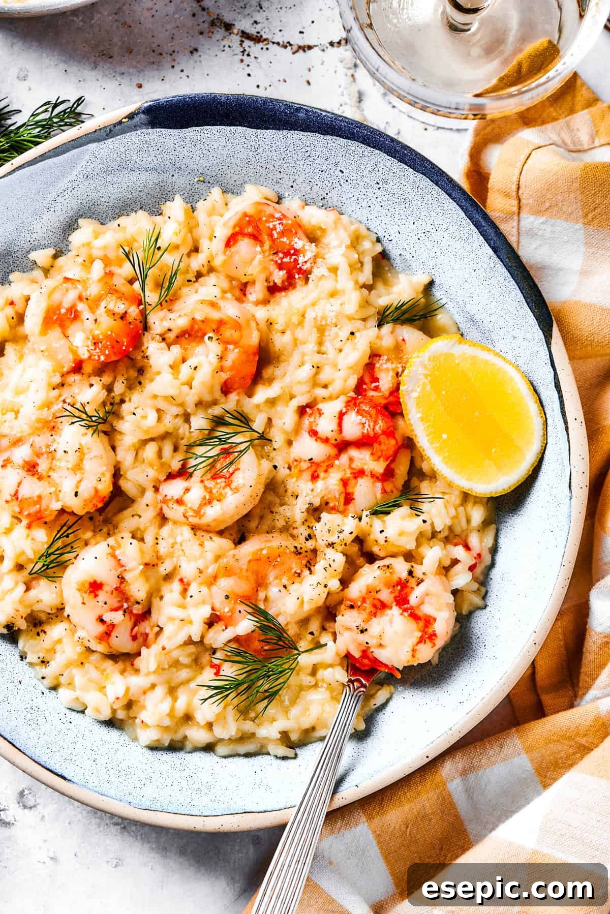 A beautifully plated serving of shrimp risotto, garnished with fresh dill and a lemon wedge.