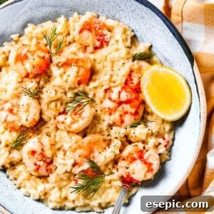 Shrimp risotto served on a plate with a wedge of lemon to the side.