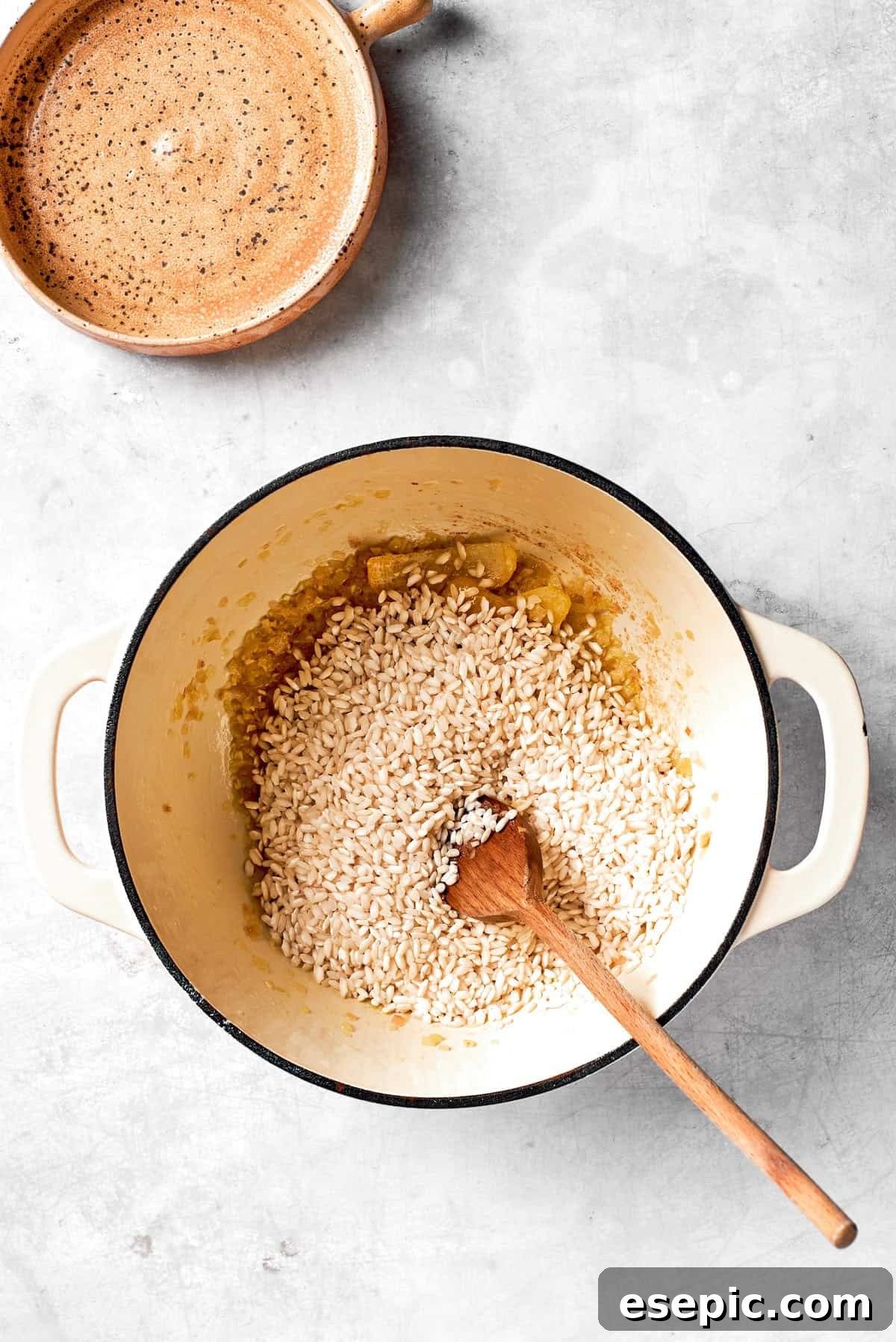 Adding Arborio rice to the sautéed aromatics in the pot, ready to be toasted.