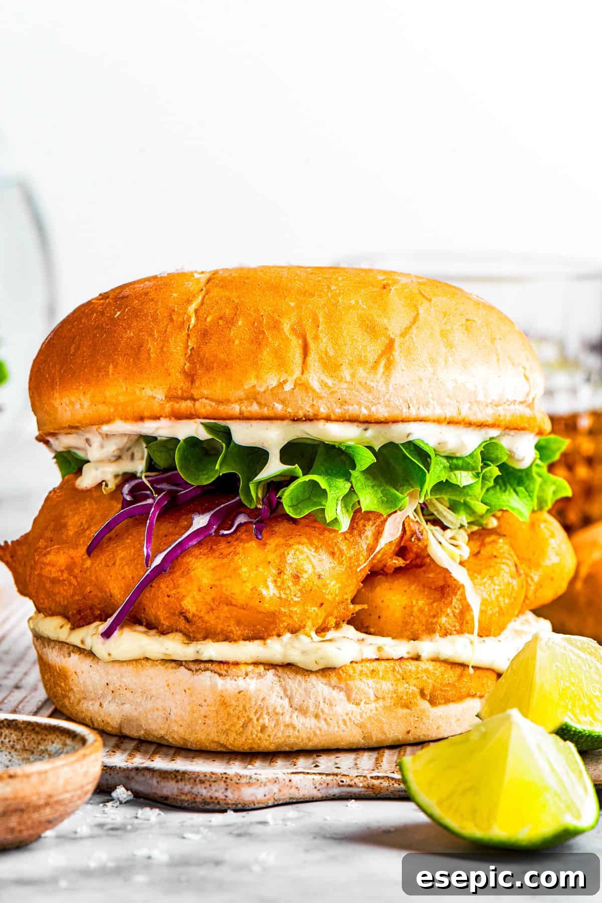 A sandwich with fried fish, lettuce, and tartar sauce.