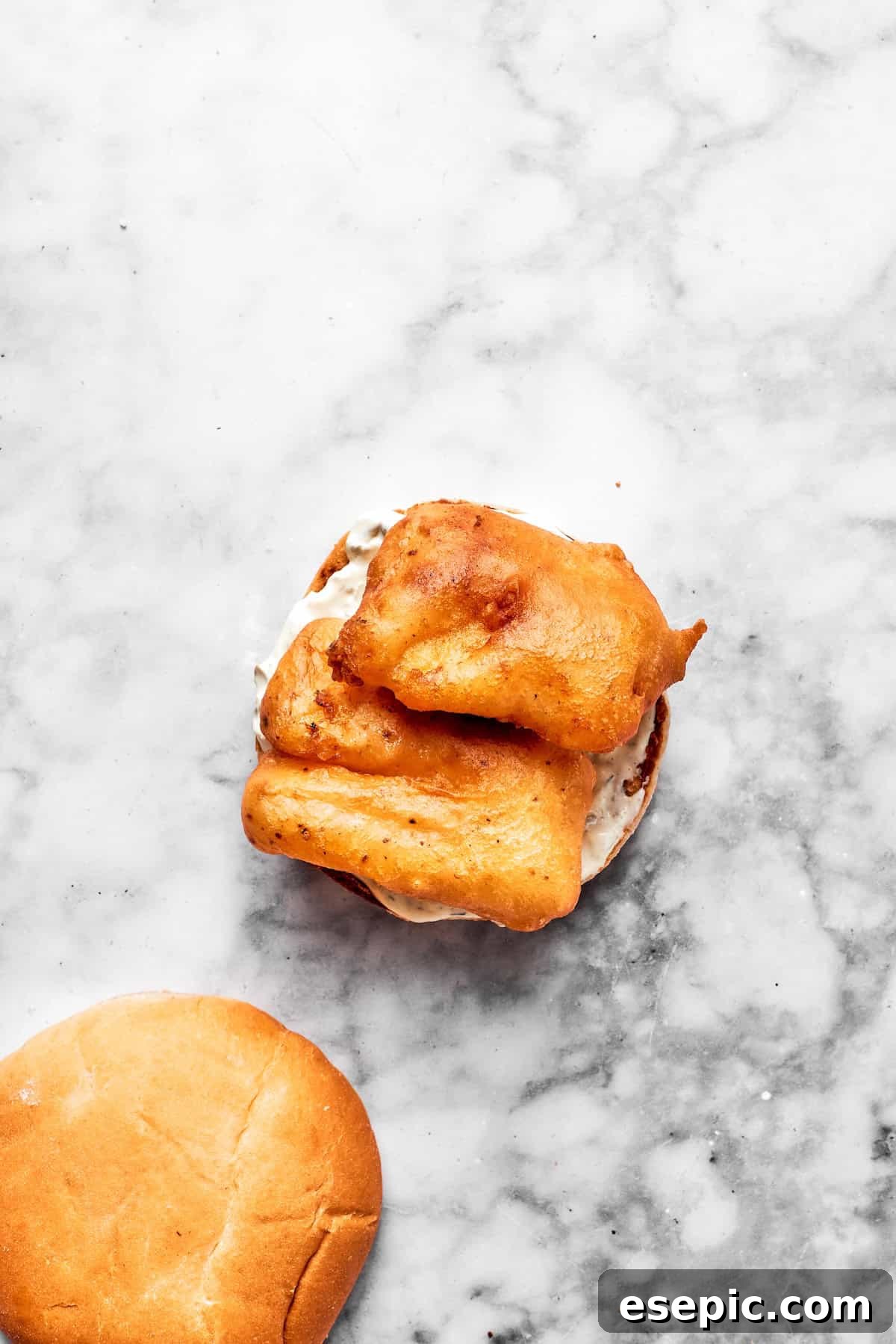 Fried fish pieces are placed on a toasted bun.