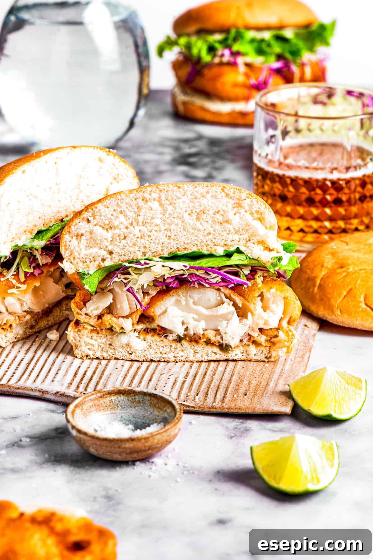 A fish sandwich cut in half and facing the camera so the contents of the sandwich are visible.