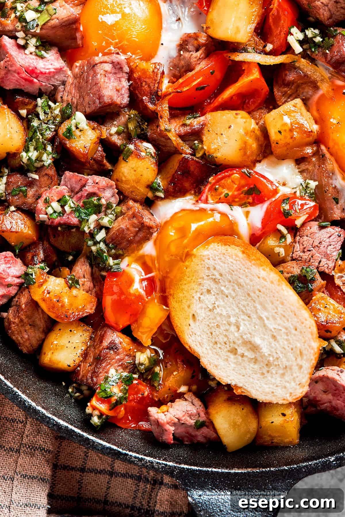 A slice of crusty baguette rests on a pan of steak and eggs, ready to soak up delicious flavors.