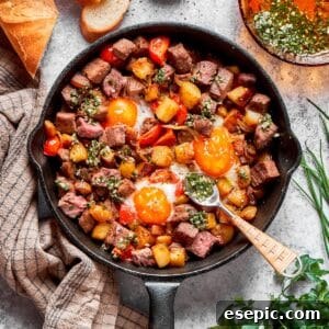 A cast iron skillet full of steak and eggs and a spoon, ready to be enjoyed.
