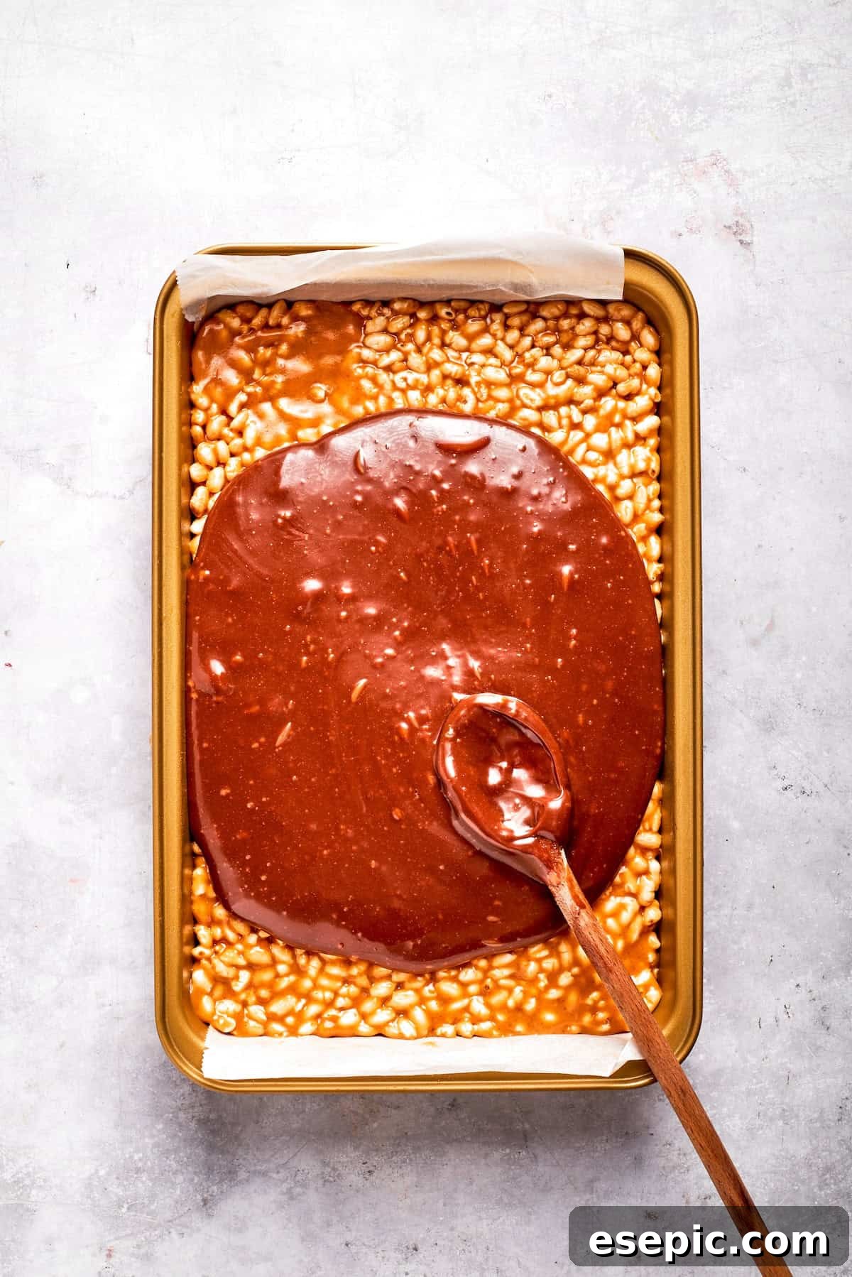 No-bake scotcharoos feature creamy peanut butter, crispy rice cereal, and a sweet layer of melted chocolate and butterscotch. Melted chocolate and butterscotch is spread over a pan of Scotcharoos, creating a smooth top layer.