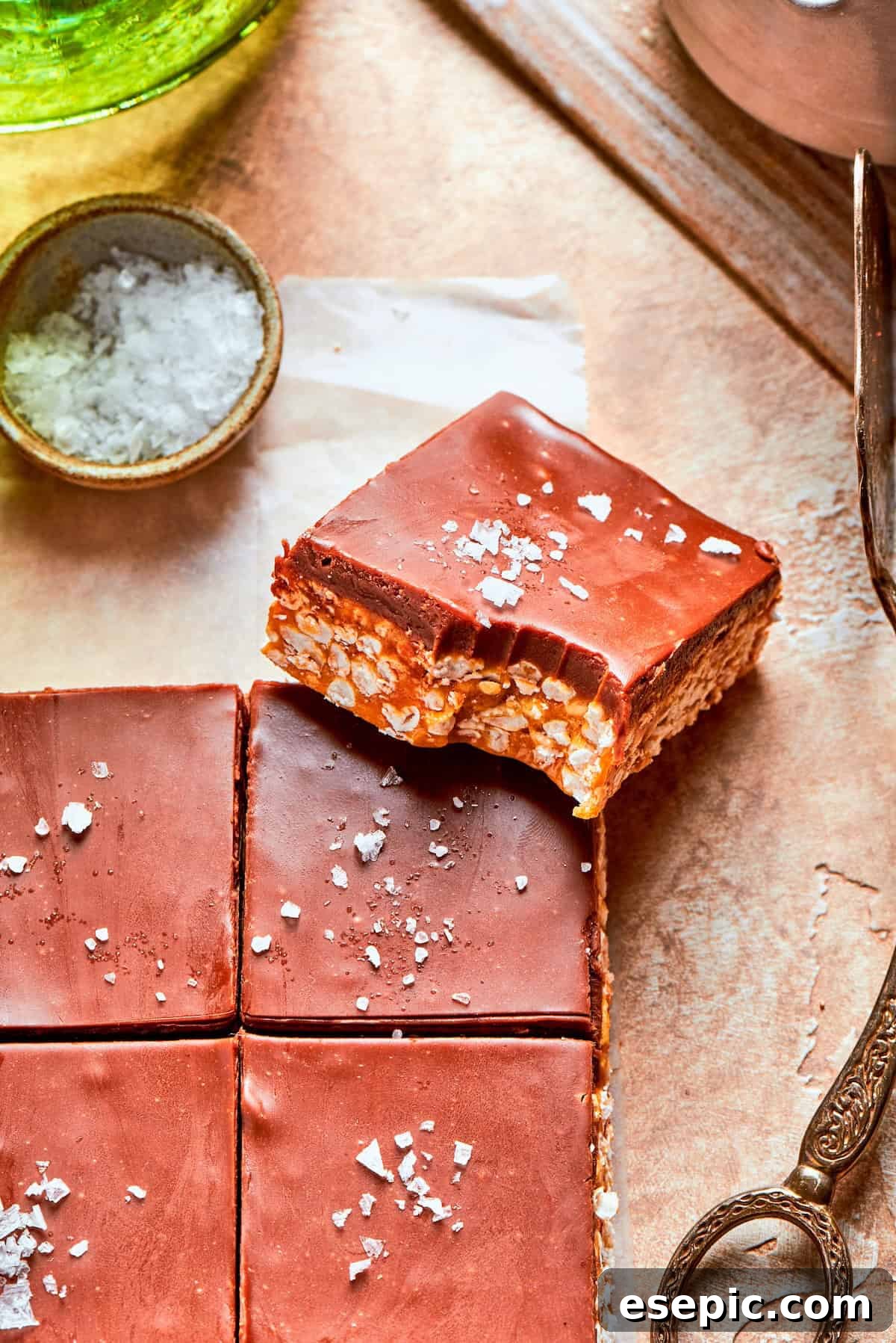 No-bake scotcharoos feature creamy peanut butter, crispy rice cereal, and a sweet layer of melted chocolate and butterscotch. A scotcharoo with a bite taken out, showing its delicious layers.