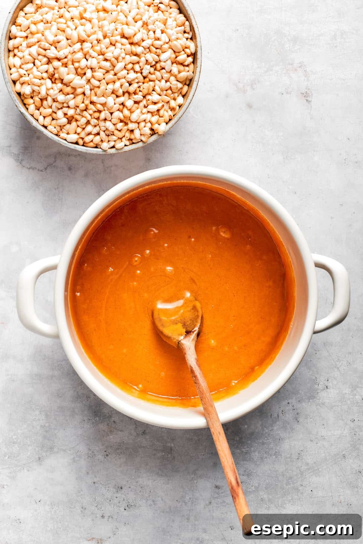 No-bake scotcharoos feature creamy peanut butter, crispy rice cereal, and a sweet layer of melted chocolate and butterscotch. Melted honey and sugar with peanut butter in a pot, being stirred.