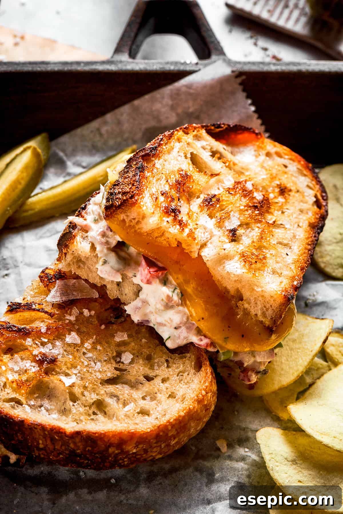 This toasty tuna melt recipe features a blend of creamy tuna salad and melty cheese stuffed between slices of sourdough and pan-fried to a crisp. Close up shot of two tuna melt sandwiches filled with creamy tuna salad and perfectly melty cheese.