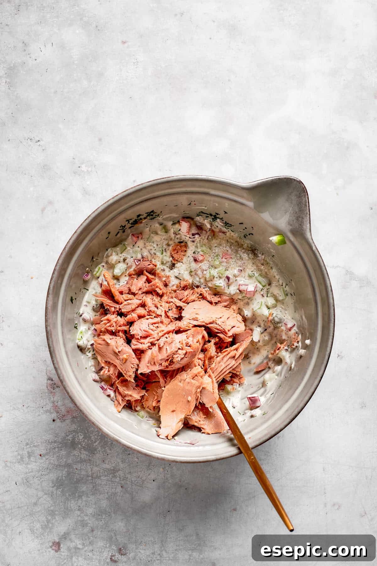 This toasty tuna melt recipe features a blend of creamy tuna salad and melty cheese stuffed between slices of sourdough and pan-fried to a crisp. Drained tuna chunks are added to the bowl with the creamy vegetable mixture, ready to be combined.