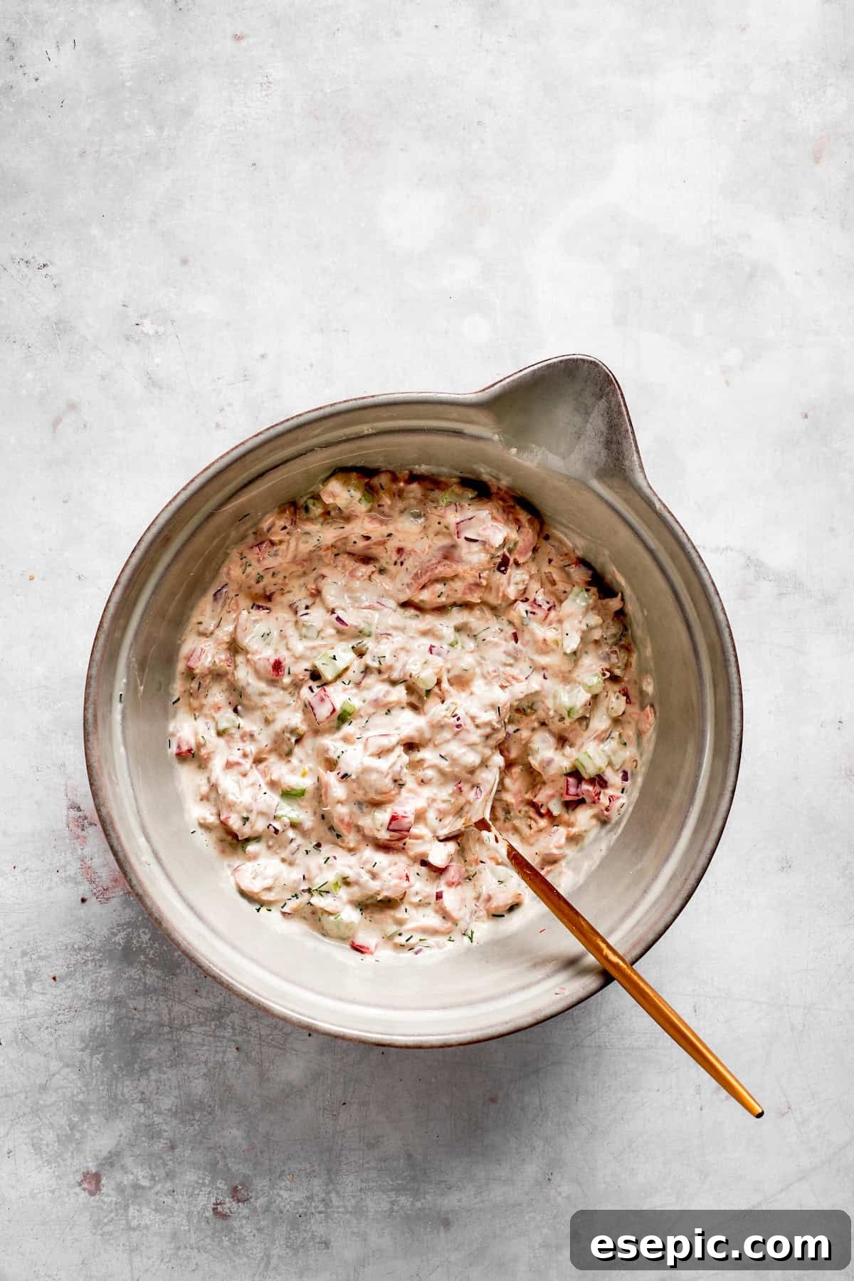 This toasty tuna melt recipe features a blend of creamy tuna salad and melty cheese stuffed between slices of sourdough and pan-fried to a crisp. The tuna melt filling is fully mixed and ready, showcasing its creamy texture with visible bits of vegetables and tuna.