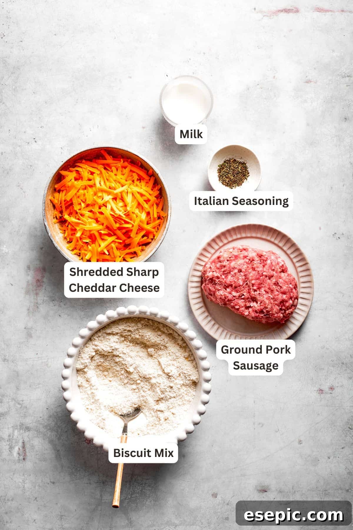 This sausage balls recipe relies on Bisquick, pork sausage, and Italian seasoning for an easy appetizer. Don't forget the dipping sauce! All the essential ingredients for making Bisquick sausage balls are laid out on a kitchen counter, each clearly labeled.