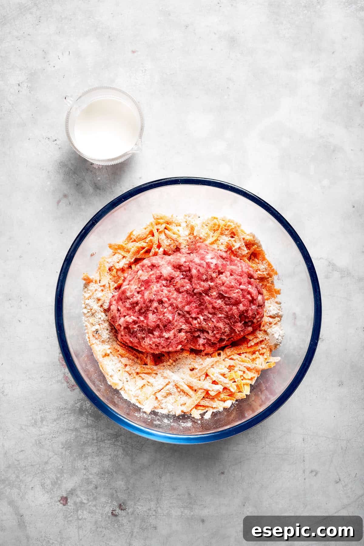 This sausage balls recipe relies on Bisquick, pork sausage, and Italian seasoning for an easy appetizer. Don't forget the dipping sauce! Biscuit mix, shredded cheddar cheese, ground pork sausage, Italian seasoning, and milk ready to be combined in a large glass mixing bowl.