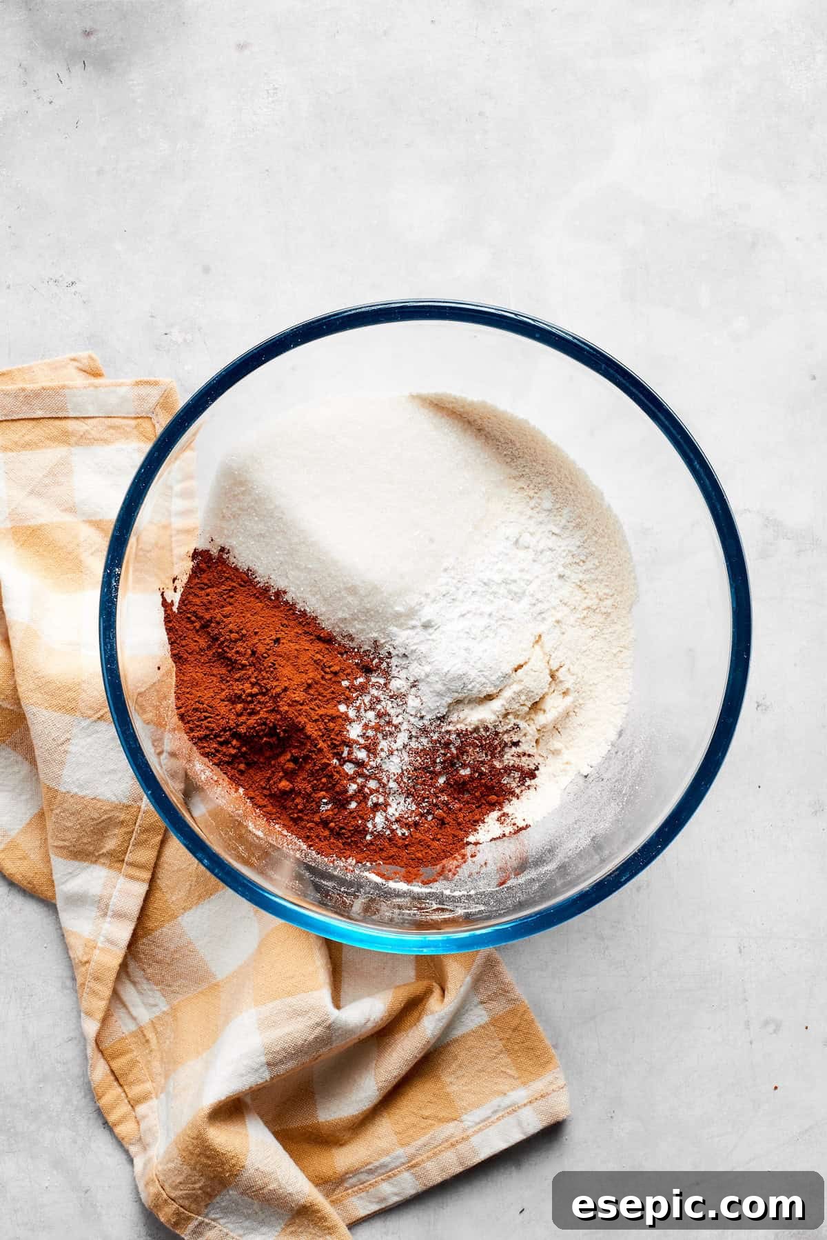 Mixing dry ingredients: flour, cocoa powder, sugar, baking powder, and salt. Dry ingredients for chocolate muffins are meticulously mixed together in a large bowl with a whisk.
