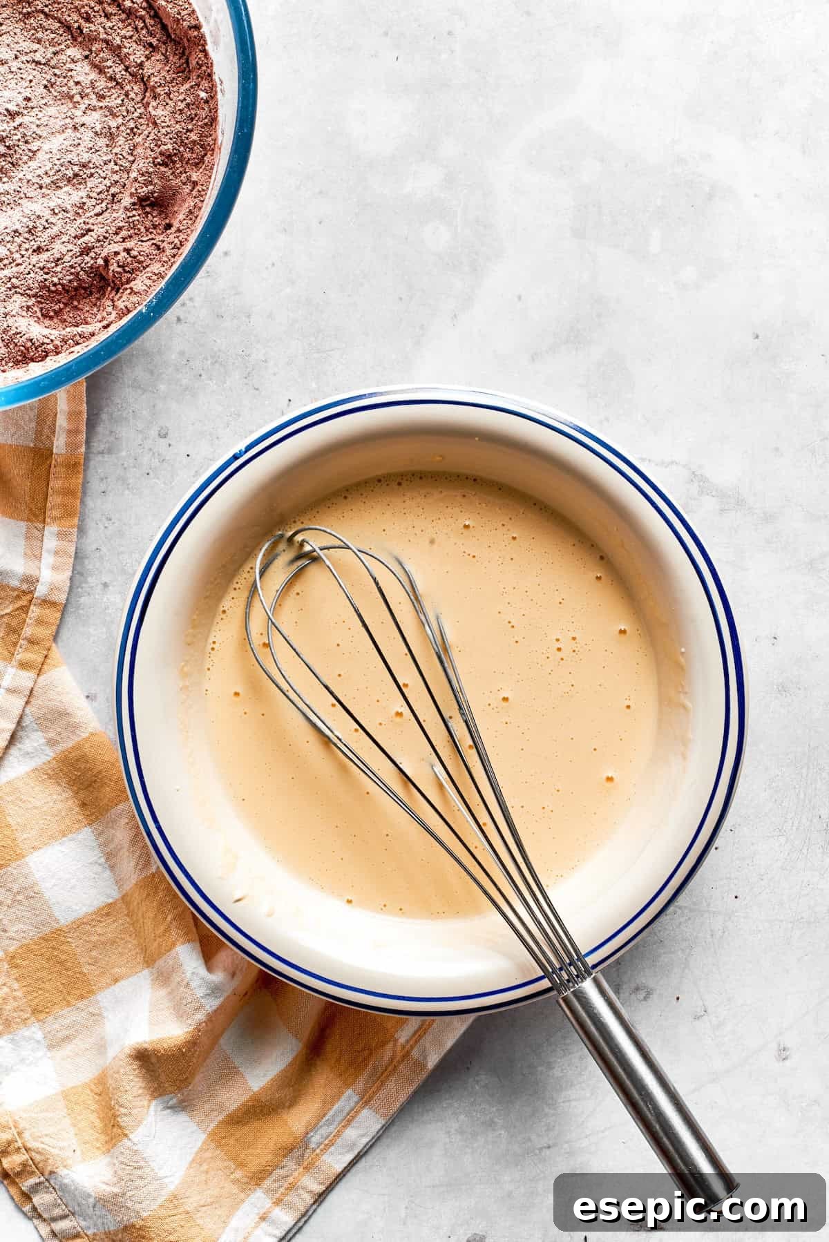 A well-whisked, smooth wet mixture ready for the next step. The wet mixture for chocolate muffins is smooth and homogenous in a bowl with a whisk.