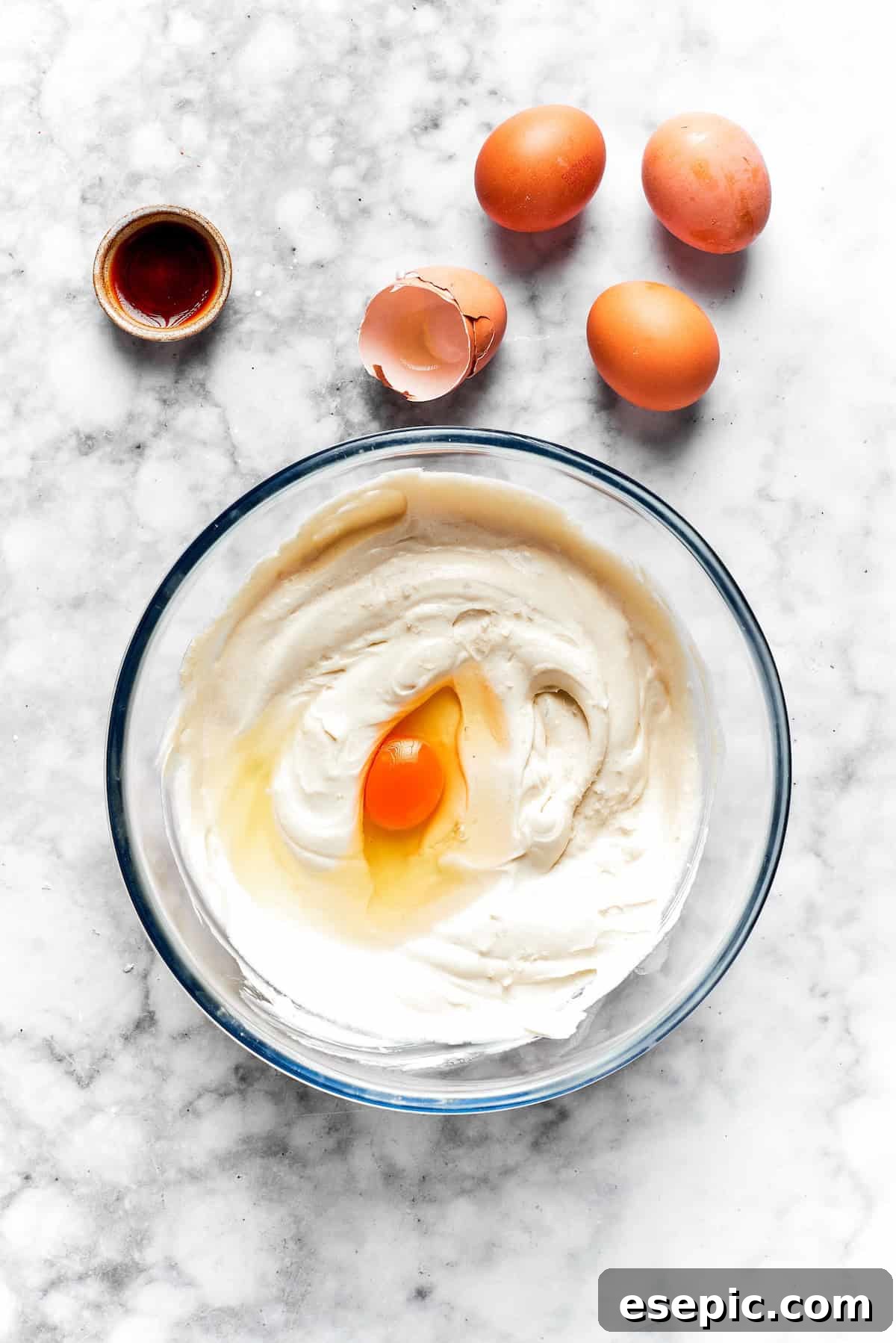 Eggs are added to cinnamon roll cheesecake batter.