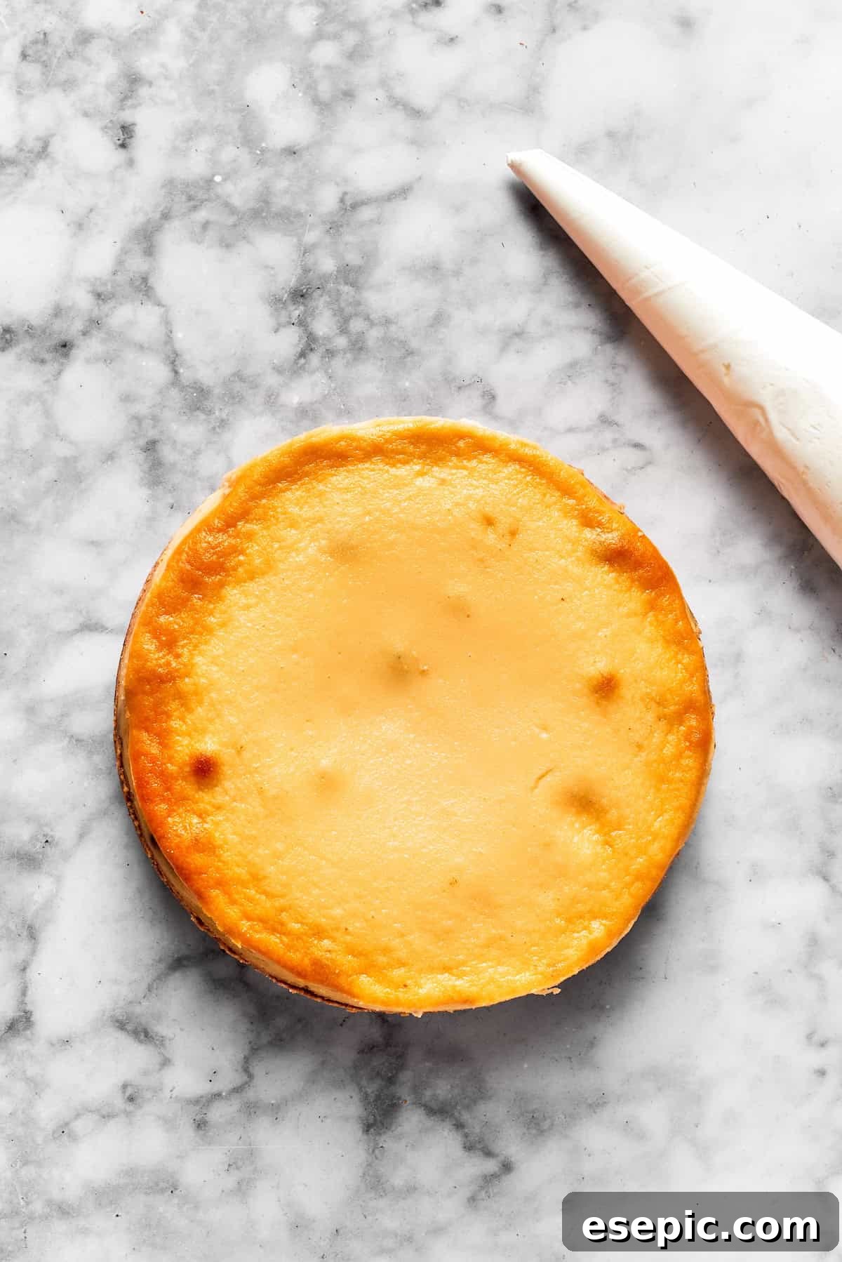 A baked cinnamon roll cheesecake with a piping bag next to it.