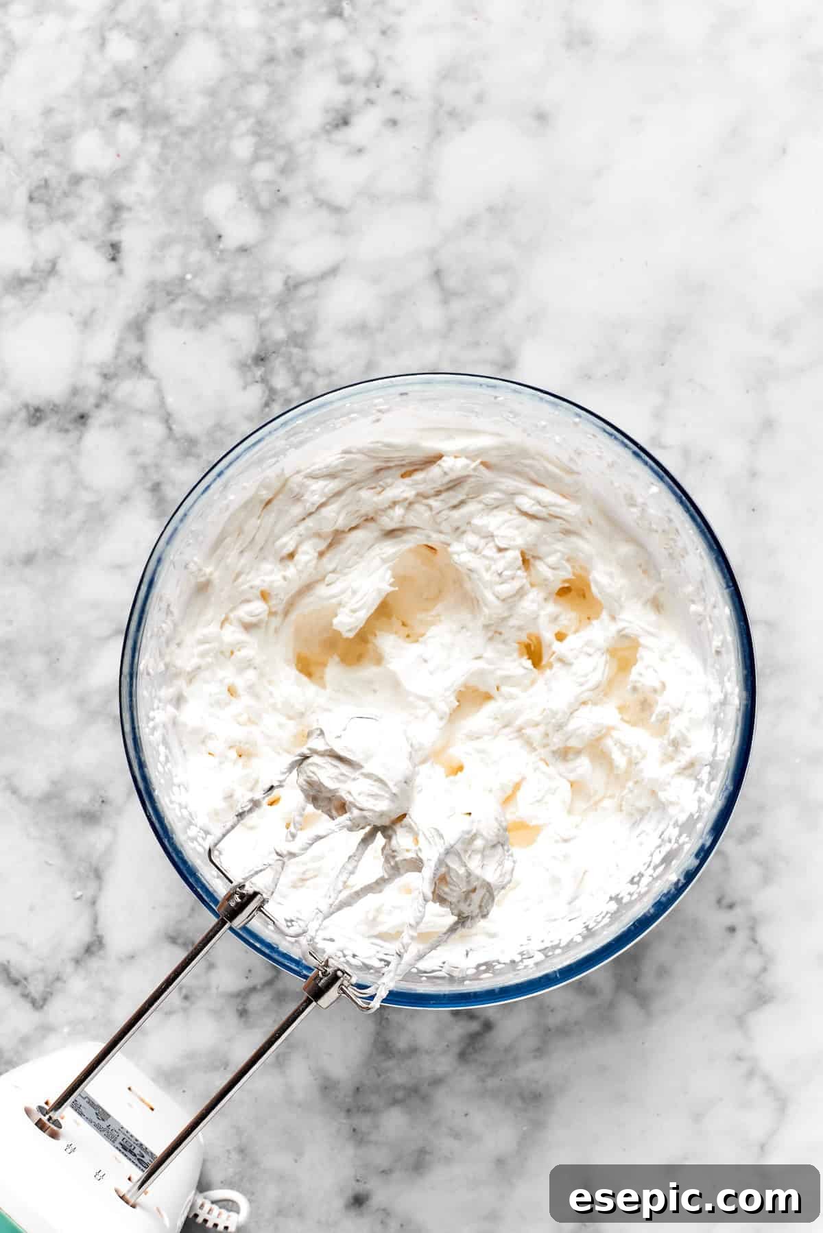 A mixer beats frosting ingredients together in a bowl.