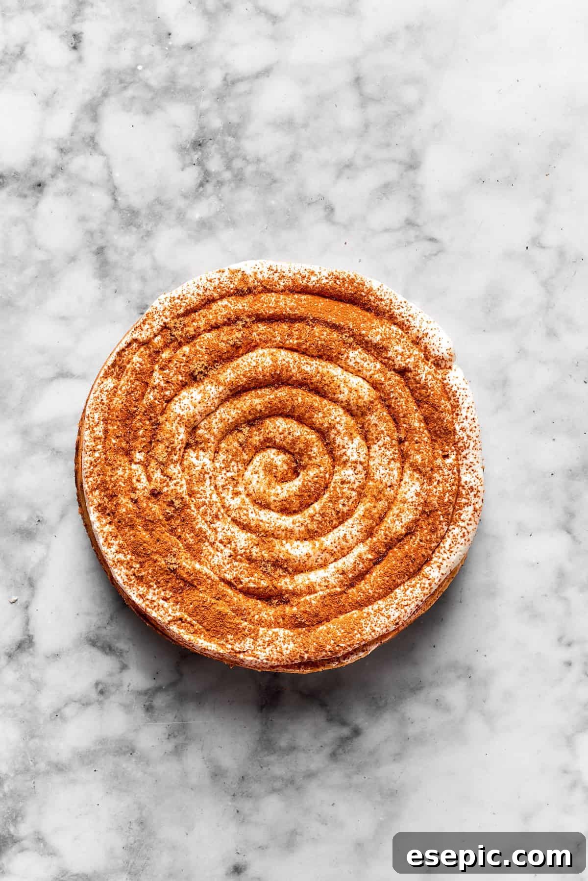 Frosting is piped onto a cinnamon roll cheesecake.