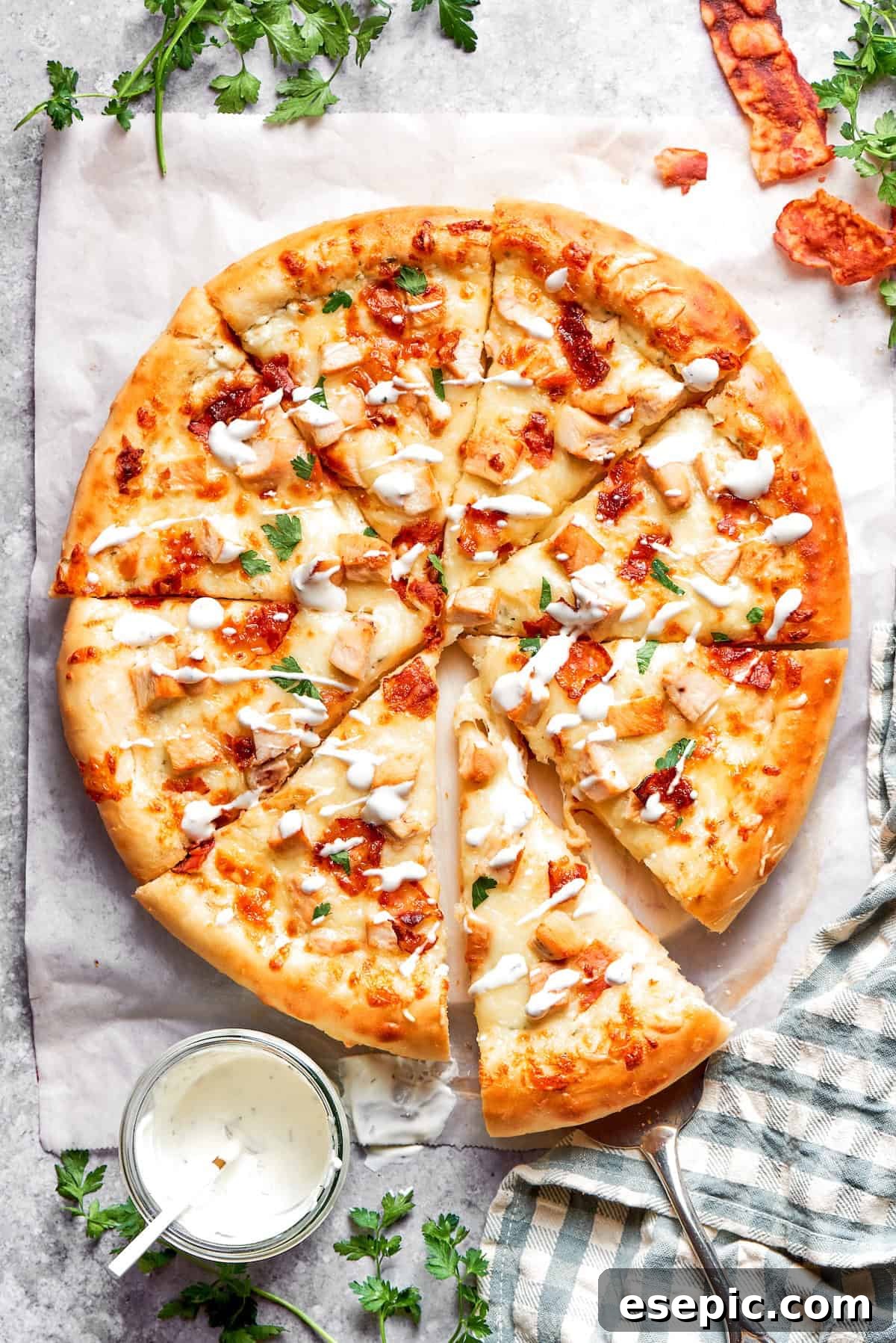 A delectable Chicken Bacon Ranch Pizza, freshly baked and served with extra Ranch dressing on the side for dipping. The golden crust, melted cheese, and ample toppings are visible.