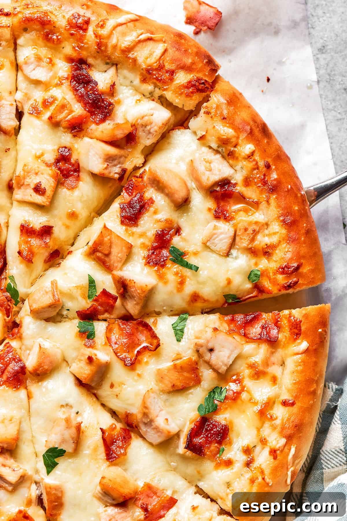 Close-up of several slices of a freshly baked Chicken Bacon Ranch Pizza, showing the golden crust, melted cheese, and visible toppings of chicken and bacon.