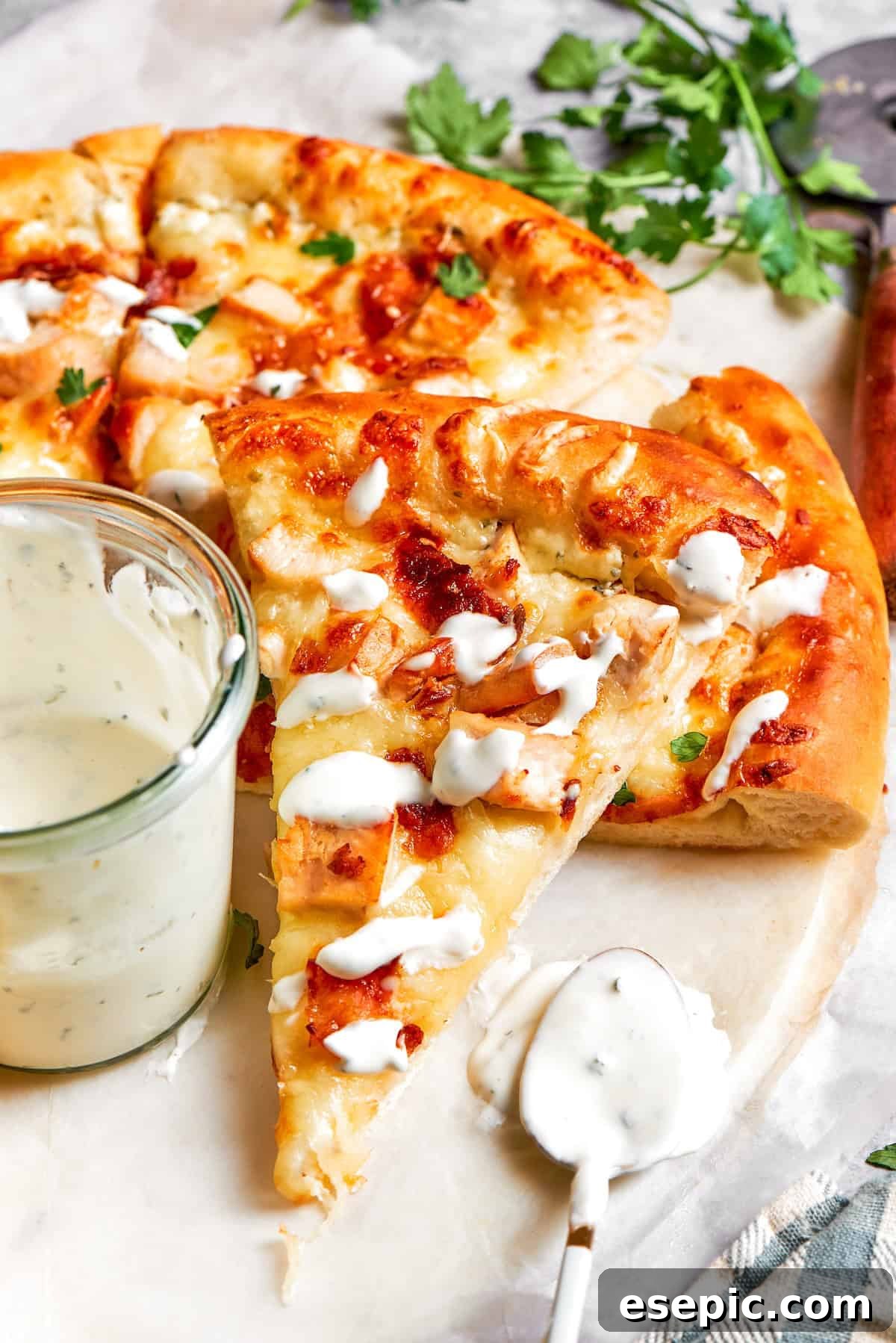 A stream of creamy Ranch sauce being drizzled over a slice of Chicken Bacon Ranch Pizza, highlighting its rich and appealing texture.
