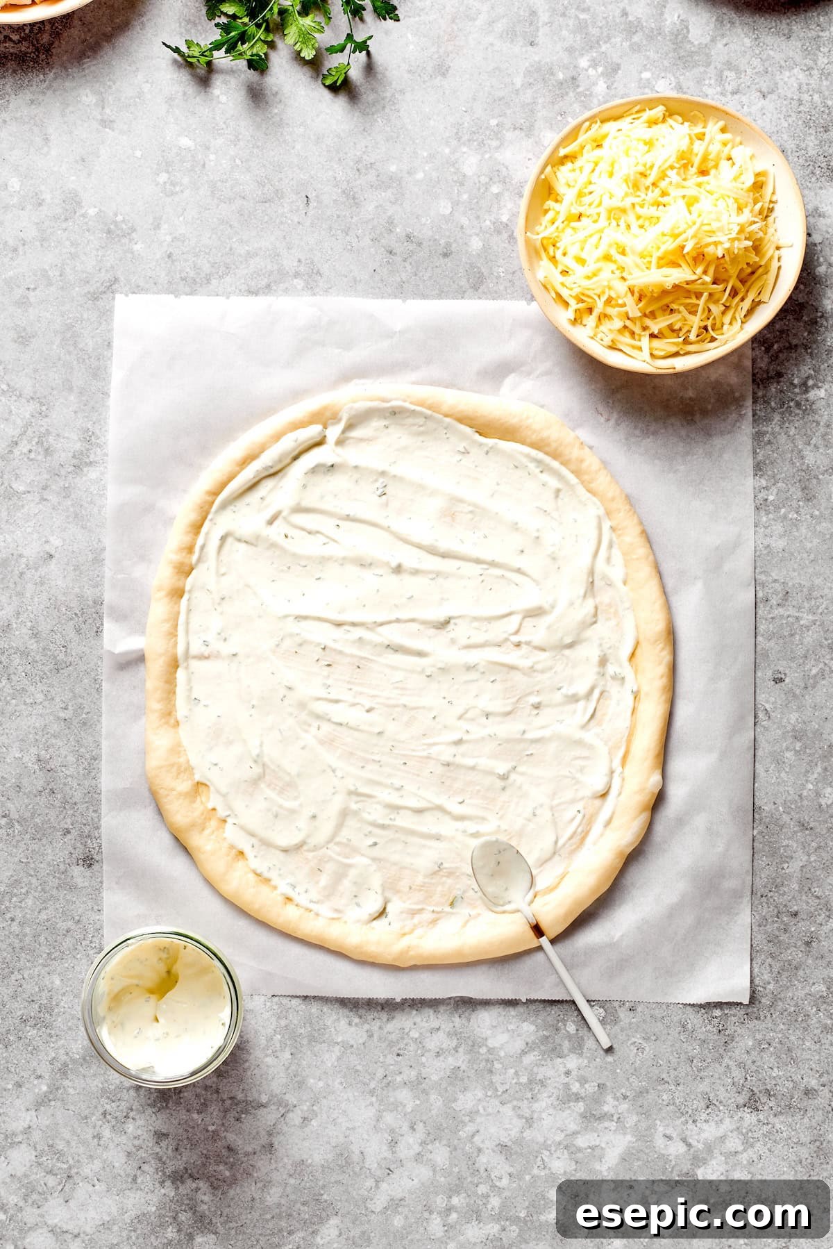 A circular pizza dough base evenly coated with a layer of creamy Ranch dressing.