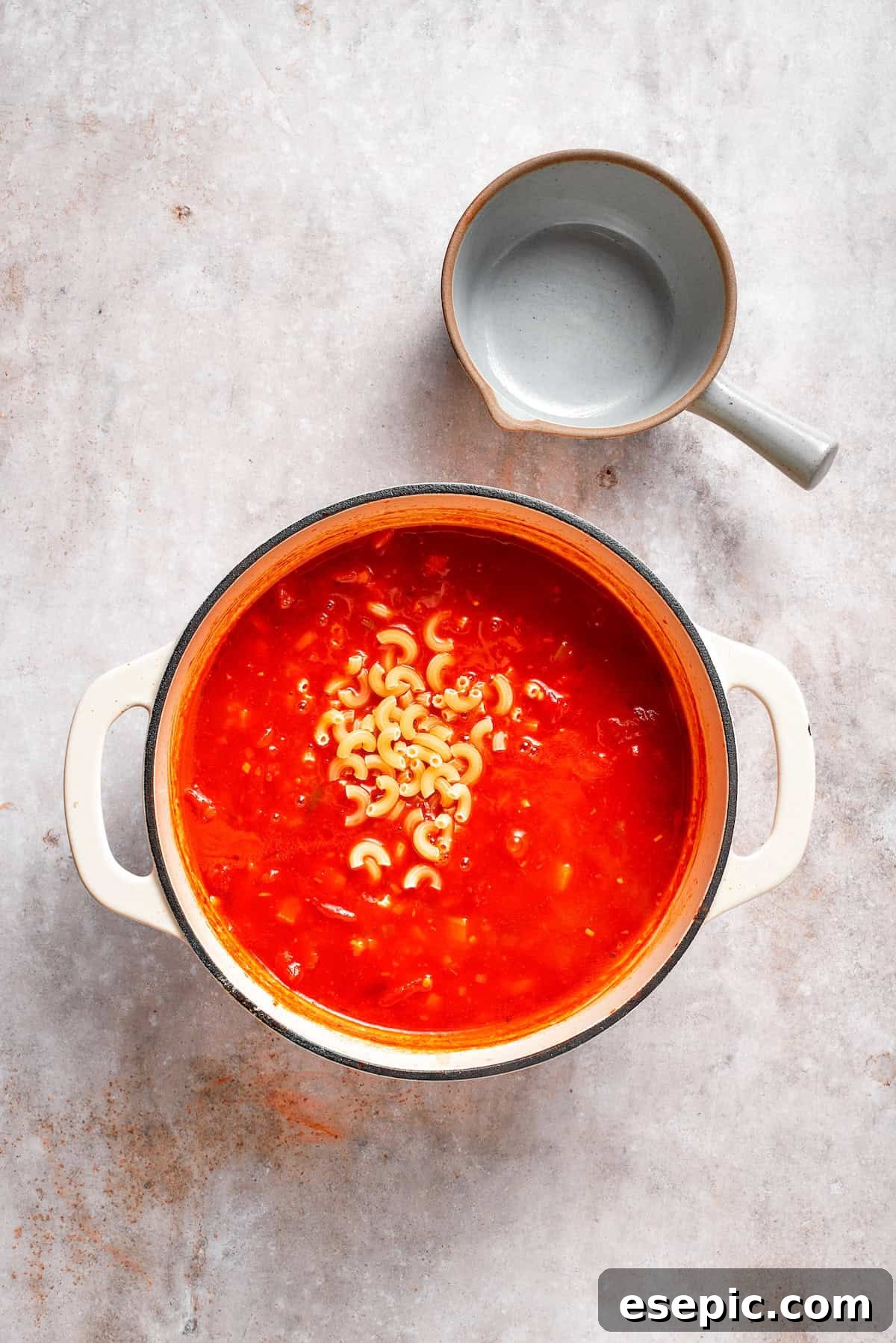 Tomato Florentine soup is deliciously hearty, packed with vegetables, herbs, spinach, and pasta simmered in a tomato-based broth. Elbow macaroni being added to a simmering pot of tomato Florentine soup.