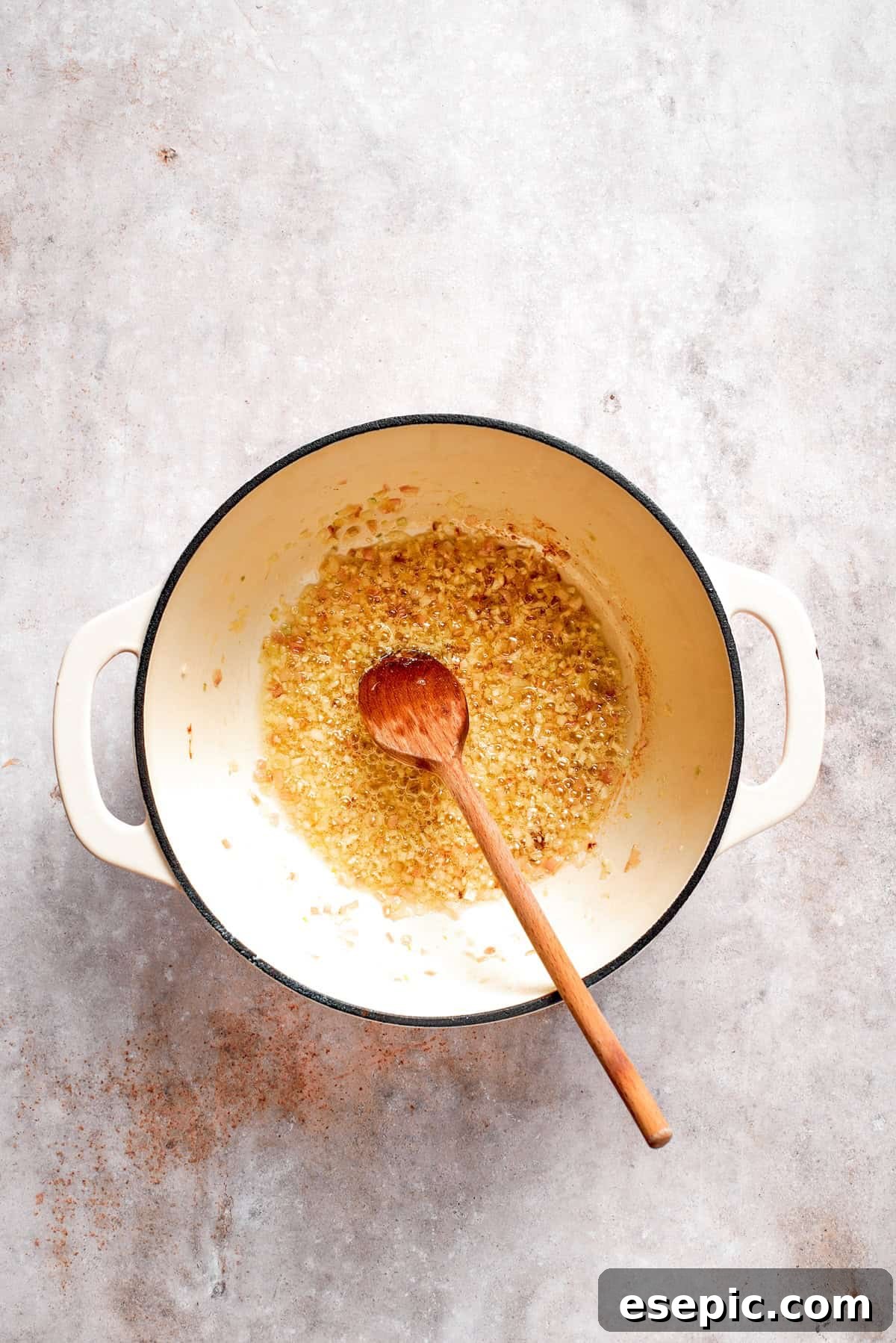 Tomato Florentine soup is deliciously hearty, packed with vegetables, herbs, spinach, and pasta simmered in a tomato-based broth. Minced garlic is added to the sautéed shallots in a soup pot, infusing the mixture with its pungent aroma.