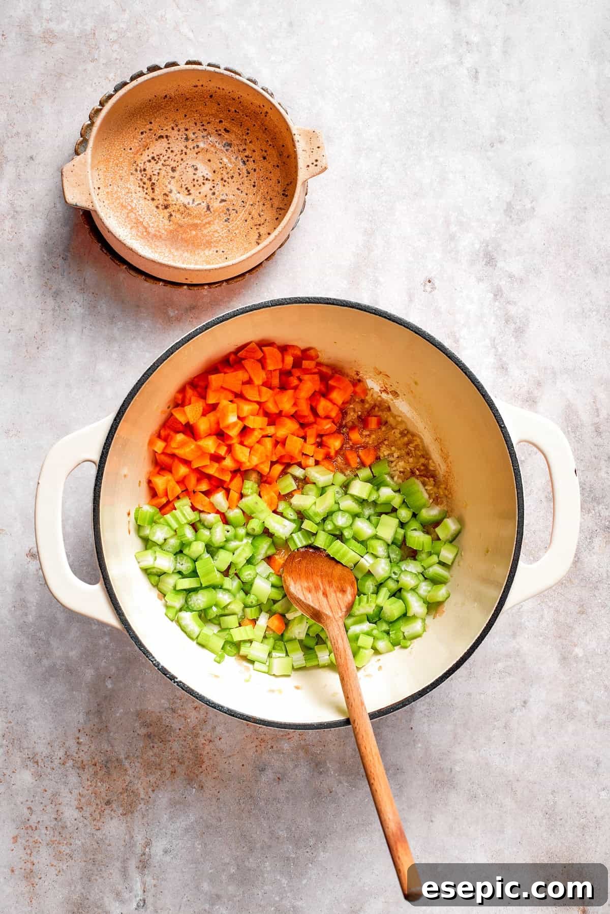 Tomato Florentine soup is deliciously hearty, packed with vegetables, herbs, spinach, and pasta simmered in a tomato-based broth. Chopped celery and carrots are added to the softened shallots and garlic in a soup pot, ready to be sautéed.