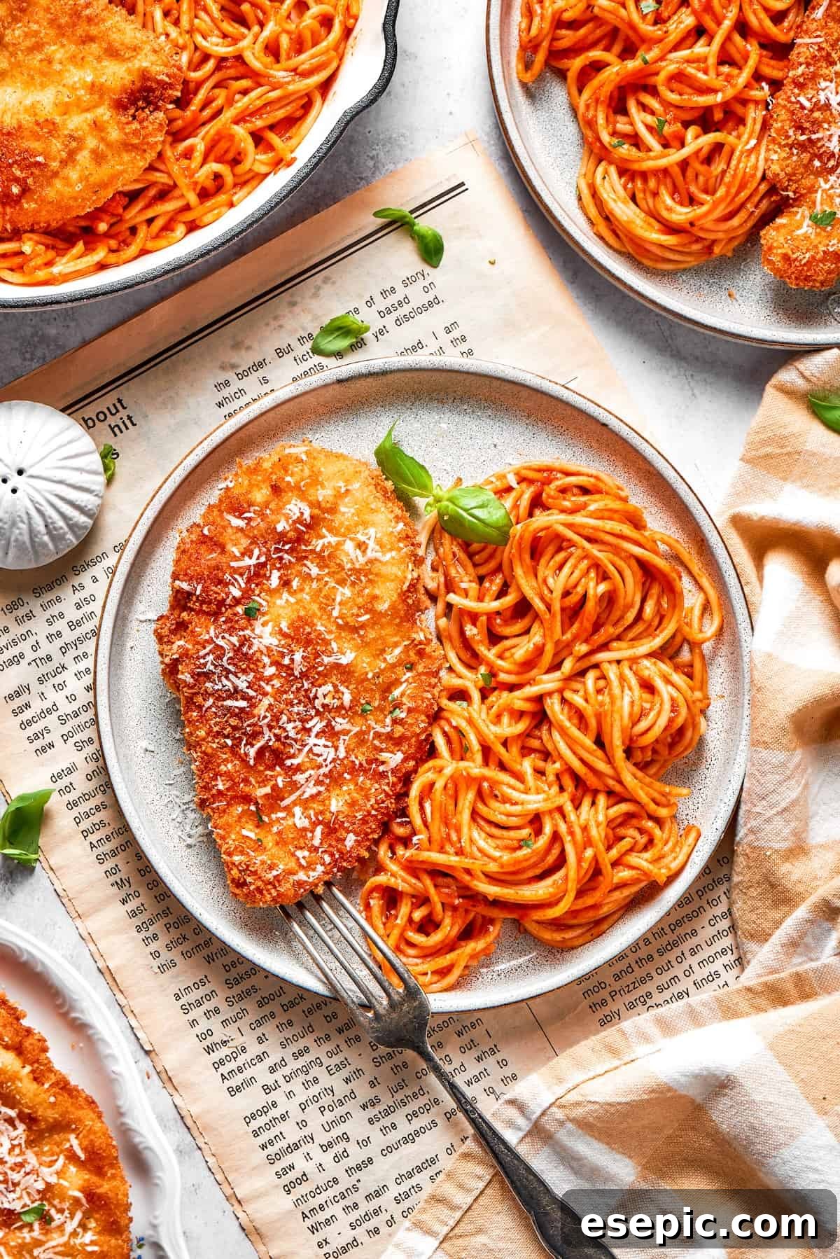 Plates of Crusted Chicken Romano, featuring crispy chicken and spaghetti with marinara sauce.