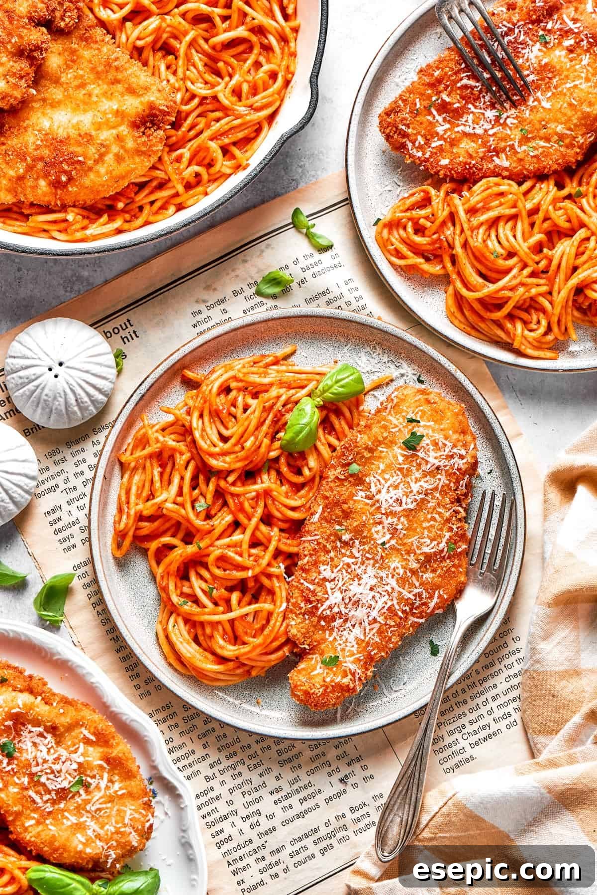 Crusted chicken romano is served on plates with pasta.