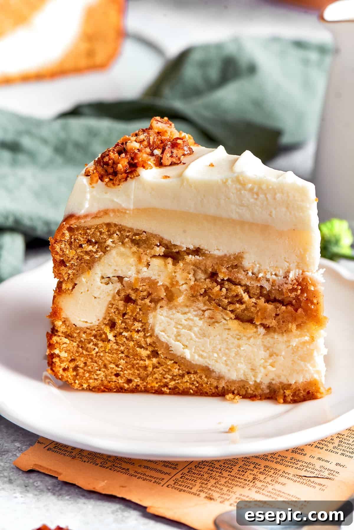 A thick slice of carrot cake cheesecake on a plate, showing distinct layers of cake and cheesecake.