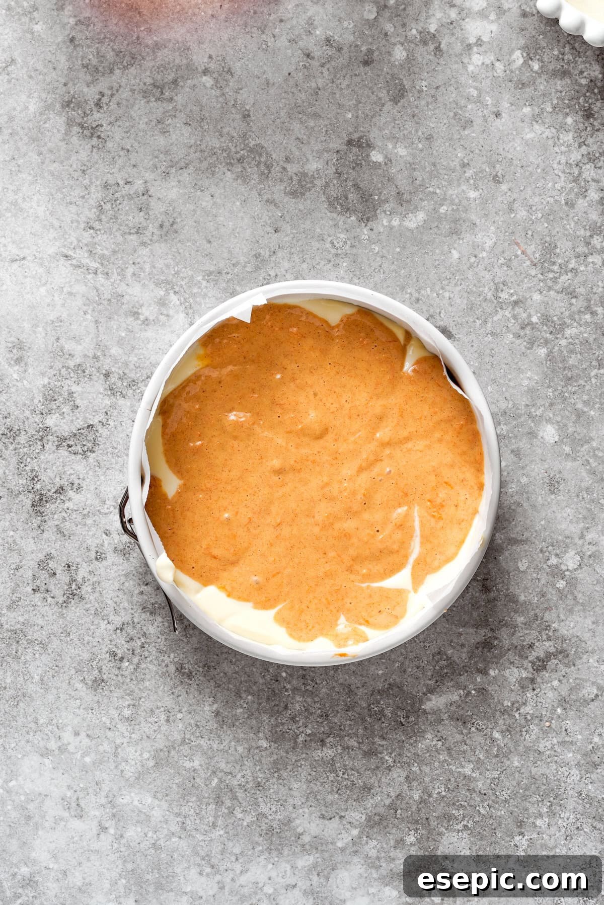 The first layer of carrot cake batter spread evenly in a springform pan.