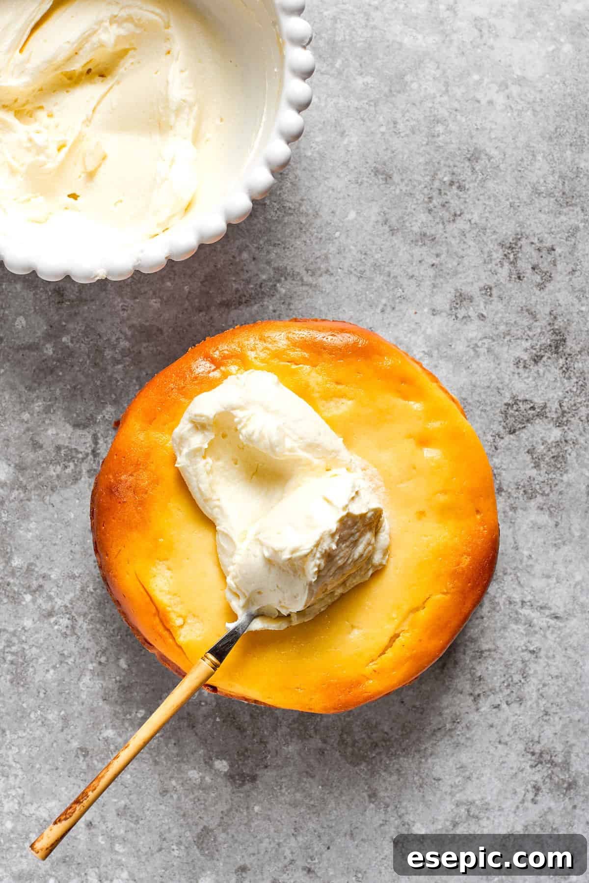 Cream cheese frosting being smoothly spread over the top of the chilled carrot cake cheesecake.