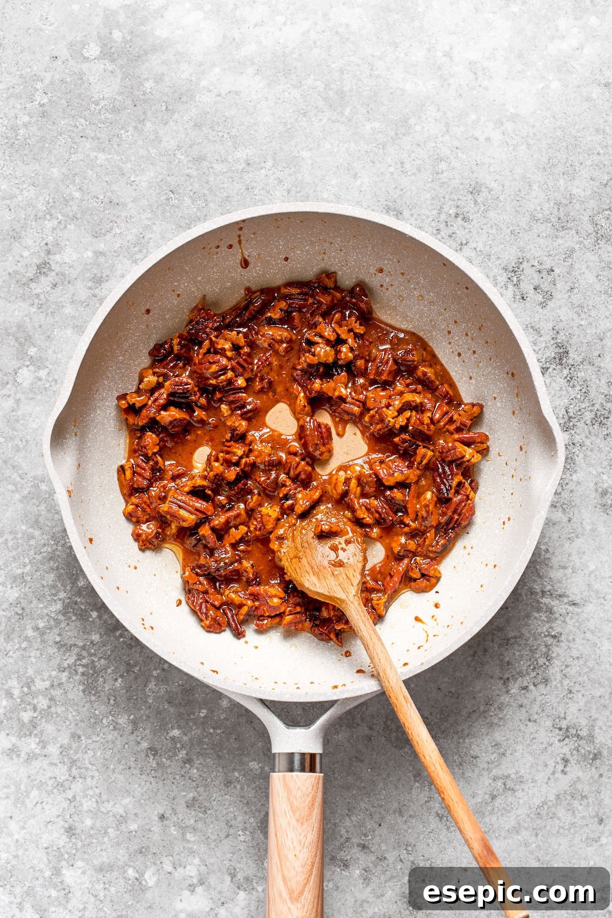Pecans being toasted with butter and sugar in a skillet, for a crunchy, sweet topping.