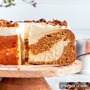 A slice is removed from a platter of carrot cake cheesecake, showing the beautiful layers.