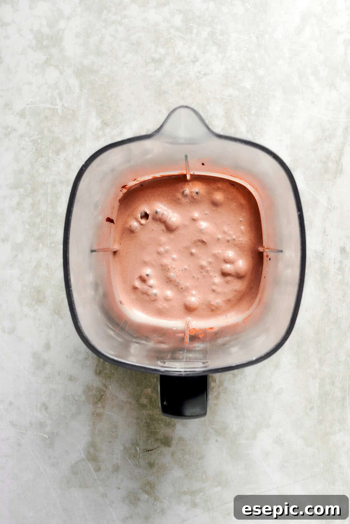 A high-powered blender is actively blending the chocolate milkshake ingredients, creating a smooth, rich mixture.